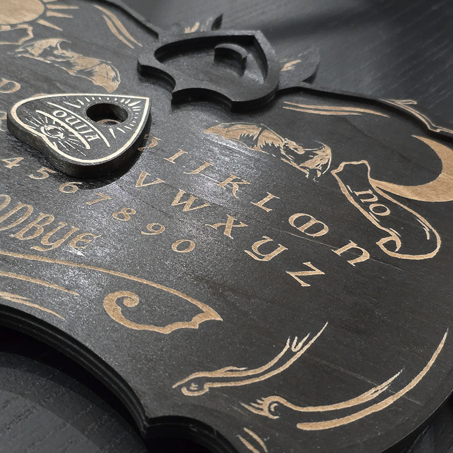 Unique black ouija board engraved and cut into wood.
