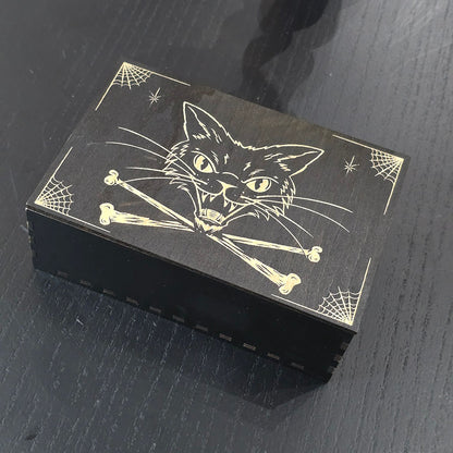 Black box with cat and bones engraved on a dark surface
